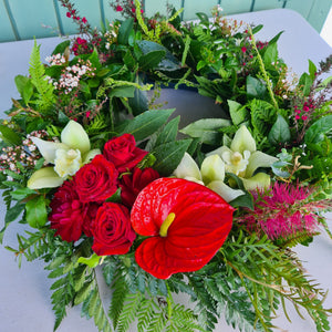 Large ANZAC wreath by Blanc Flowers in red and green features NZ and Australian native plants with an arc of flowers