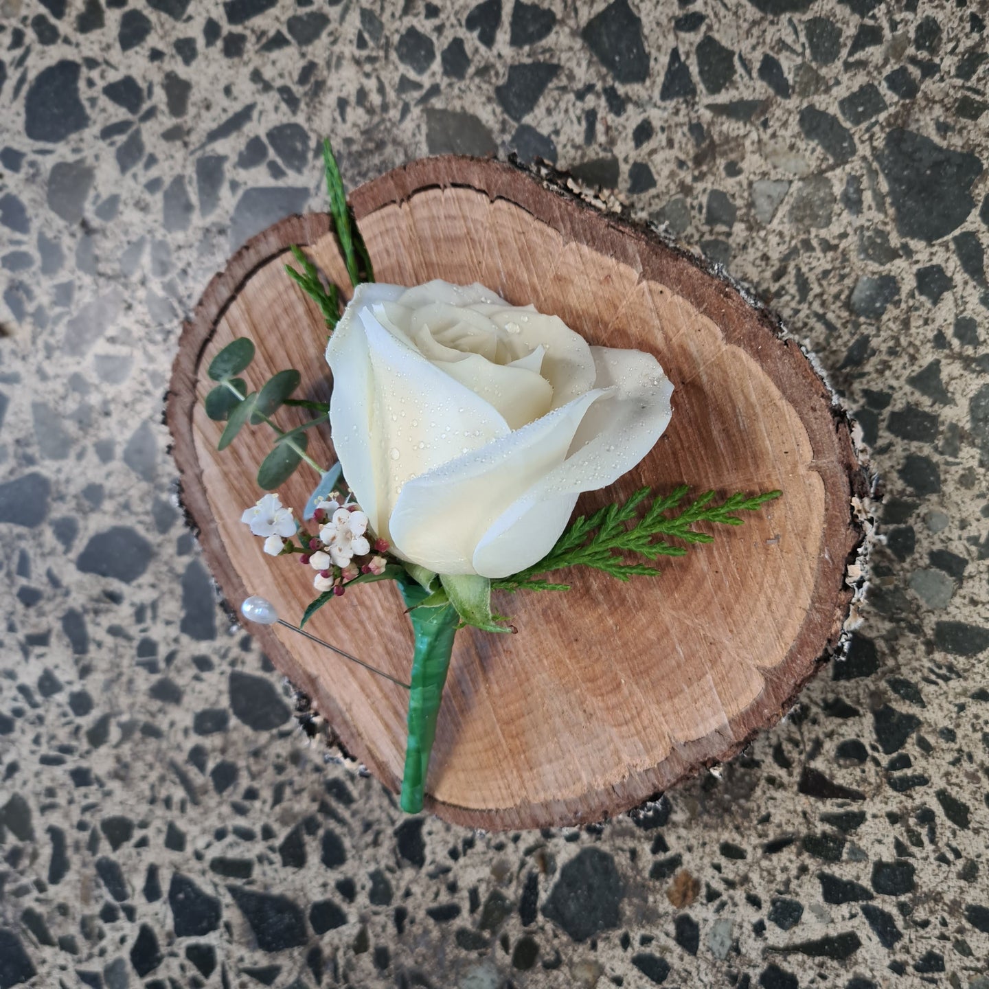 Single perfect white rose with small amount of foliage to create a stunning boutonniere