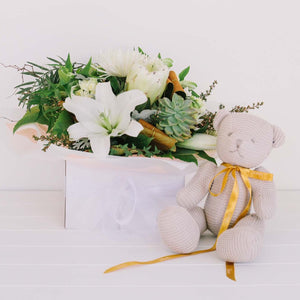 Boxed posy of easy care seasonal signature white blooms and foliage, accompanied by the cute knitted classic teddy bear in neutral colour. Regular size.